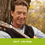 John Dady pictured with his guitar under a tree